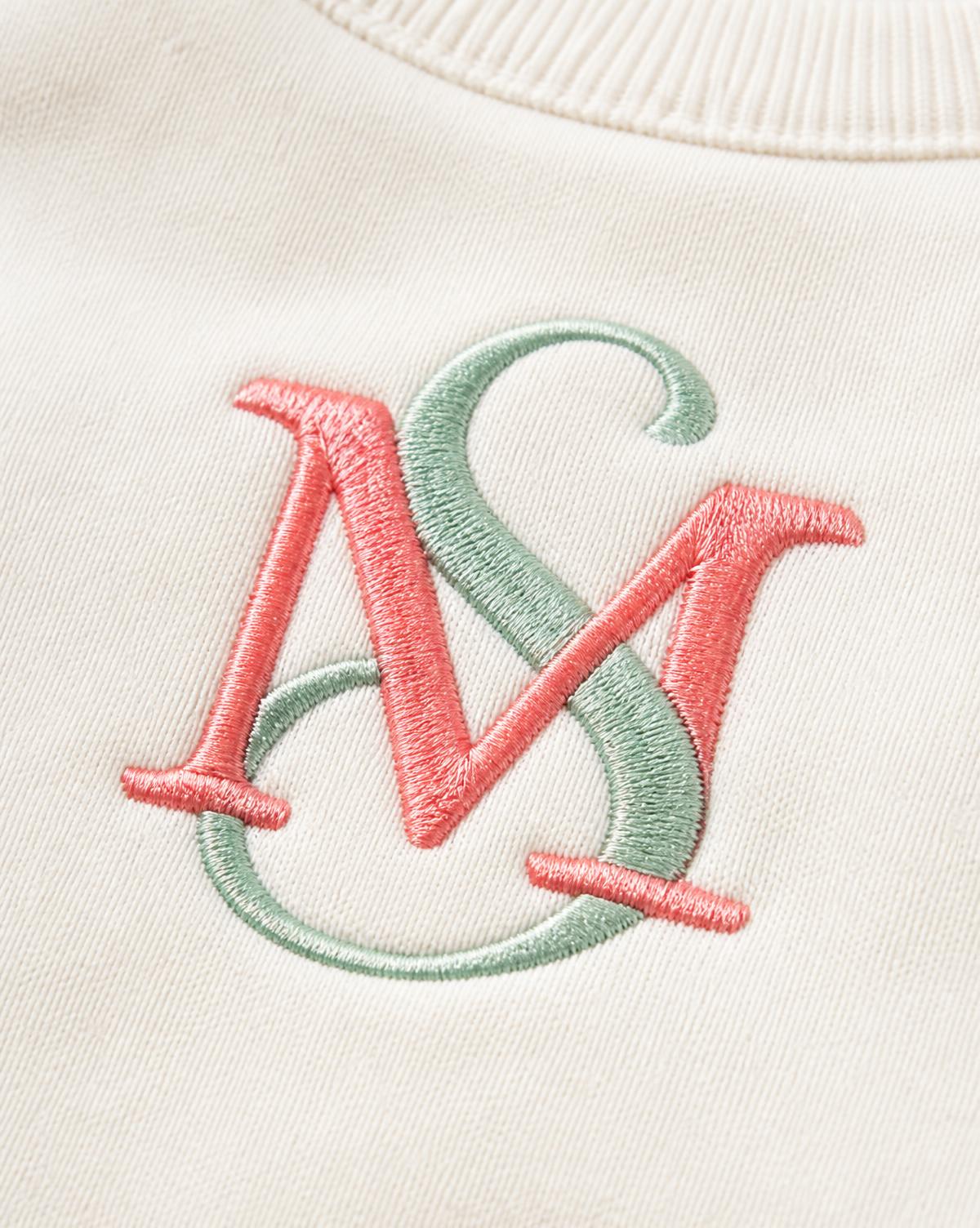 Monograma bordado en hilo coral y verde menta sobre sudadera color hueso